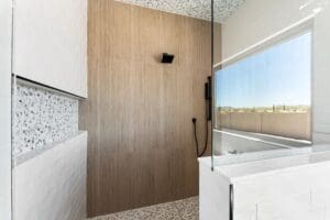 Modern walk-in shower featuring a sleek wood-look tile accent wall, minimalist black hardware, and a frameless glass enclosure for a spa like feel in Arizona