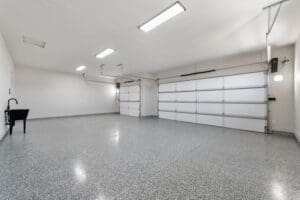 Spacious three-car garage featuring professional epoxy flooring, bright overhead lighting, and clean white walls, highlighting the high-quality finish of this custom home build