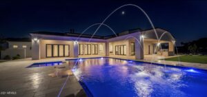 Integrated design-build custom home and luxury zero-edge pool with integrated spa and deck jets in Paradise Valley, AZ, featuring a modern architectural casita at night.