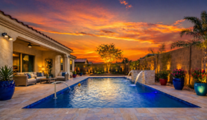  Backyard with swimming pool, stone pavers, artificial turf, water features, and plants at sunset.