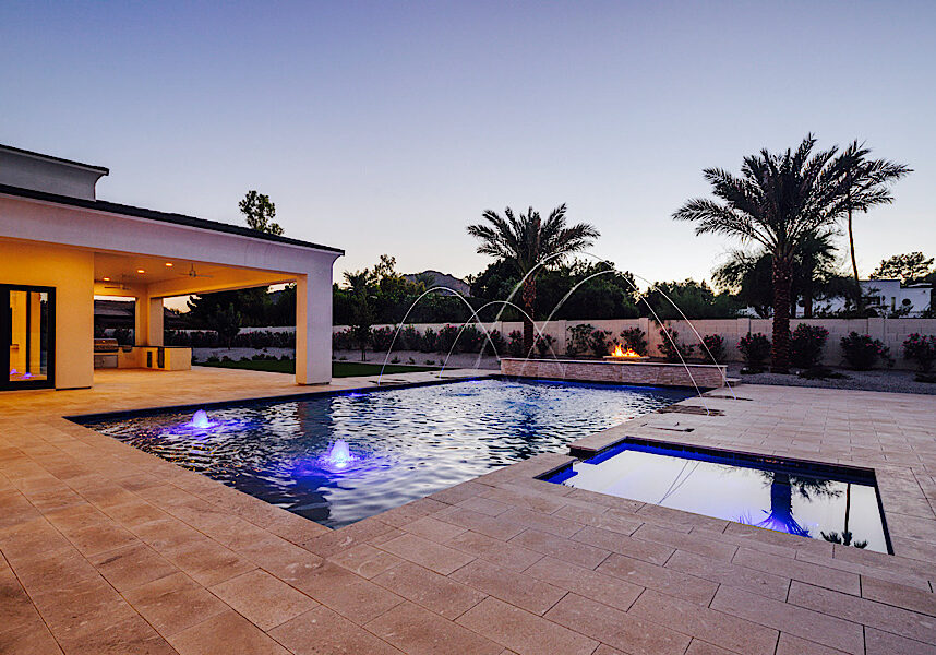 Luxury custom swimming pool in Queen Creek, AZ featuring a custom swimming pool, linear fire feature, modern patio design, and seamless indoor-outdoor living.
